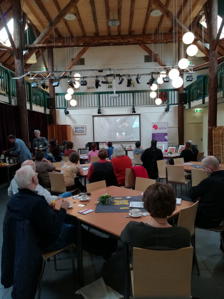 zaal met mensen die kijken naar video in het Stigma Café